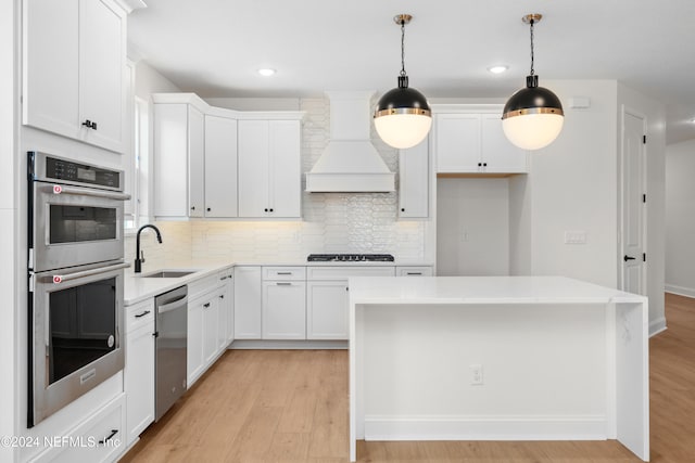 kitchen featuring custom exhaust hood, a center island, sink, light wood-type flooring, and stainless steel appliances