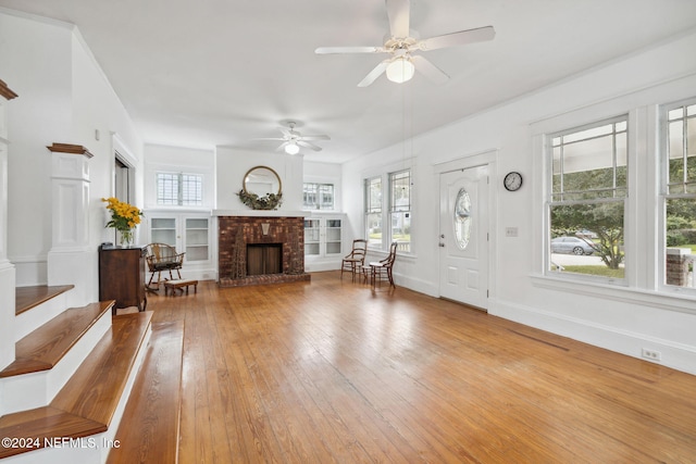 unfurnished living room featuring a brick fireplace, ceiling fan, and hardwood / wood-style flooring