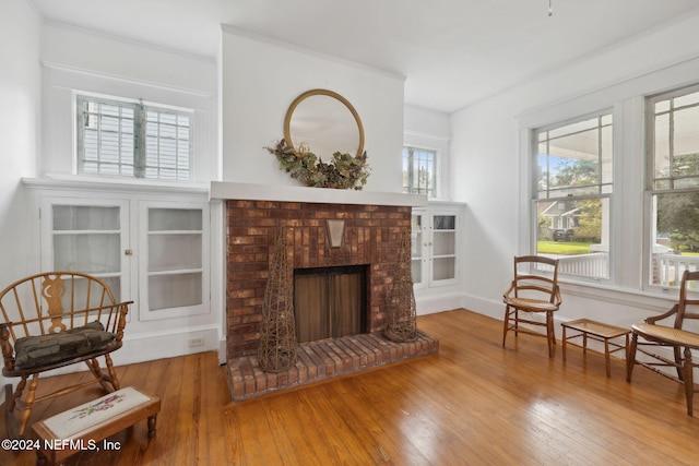 sitting room featuring hardwood / wood-style floors, a brick fireplace, and crown molding