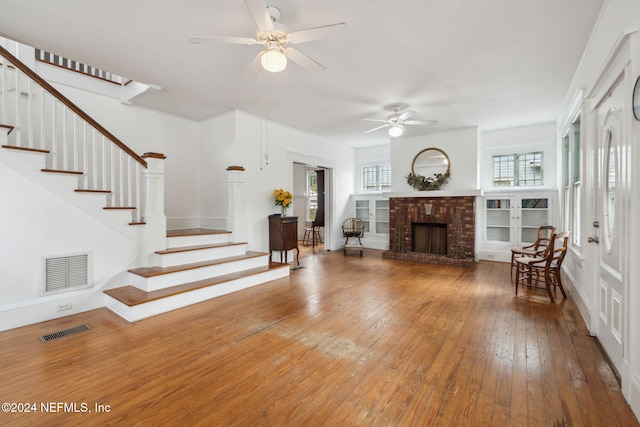 living room featuring hardwood / wood-style floors, a brick fireplace, and ceiling fan