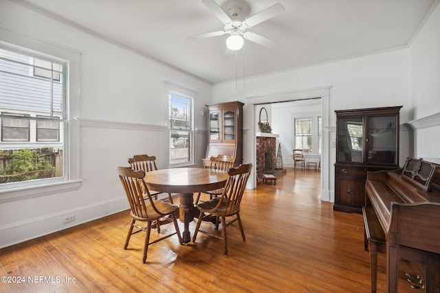 dining room featuring a fireplace, hardwood / wood-style floors, ceiling fan, and ornamental molding