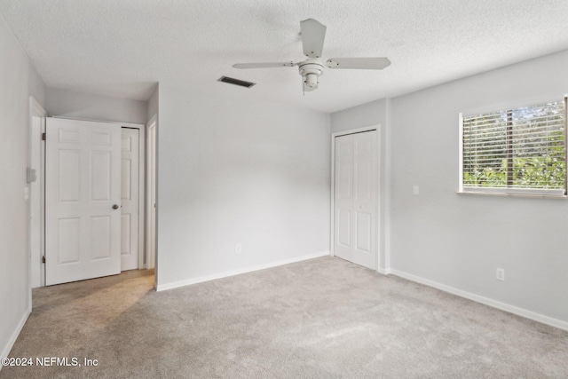 spare room featuring light carpet, a textured ceiling, and ceiling fan