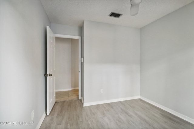 spare room featuring a textured ceiling and light hardwood / wood-style flooring