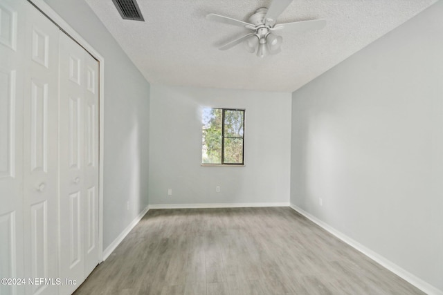 unfurnished bedroom featuring ceiling fan, light hardwood / wood-style floors, a textured ceiling, and a closet