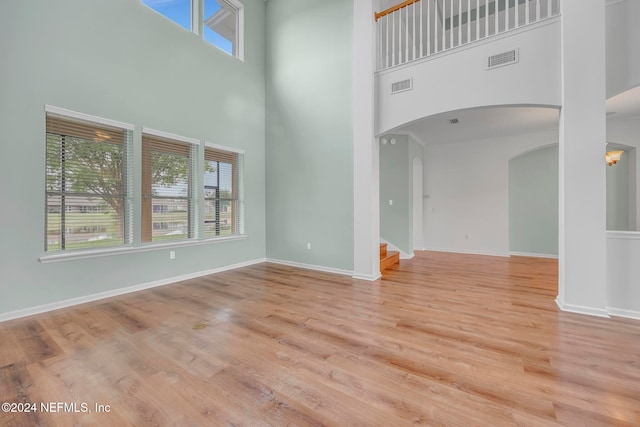 unfurnished living room featuring a high ceiling and light wood-type flooring