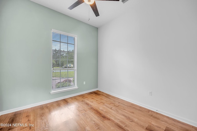 spare room with plenty of natural light, wood-type flooring, and ceiling fan