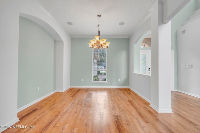 spare room with a textured ceiling, a notable chandelier, light hardwood / wood-style floors, and crown molding