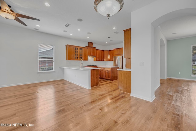 kitchen featuring stainless steel refrigerator, sink, kitchen peninsula, ceiling fan, and light hardwood / wood-style flooring