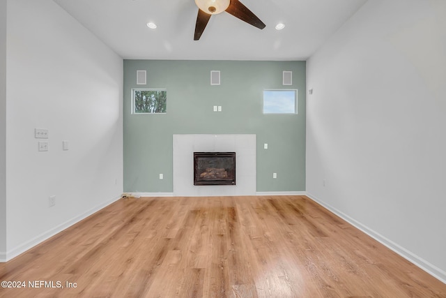 unfurnished living room with light hardwood / wood-style flooring, a healthy amount of sunlight, ceiling fan, and a tile fireplace