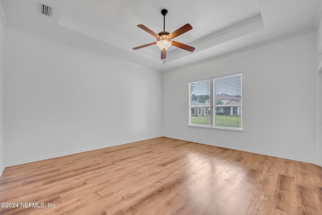 unfurnished room featuring light hardwood / wood-style floors, ceiling fan, crown molding, and a tray ceiling