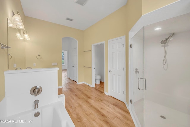 bathroom featuring toilet, independent shower and bath, and wood-type flooring