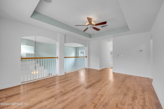 spare room with ceiling fan, light hardwood / wood-style flooring, and a tray ceiling