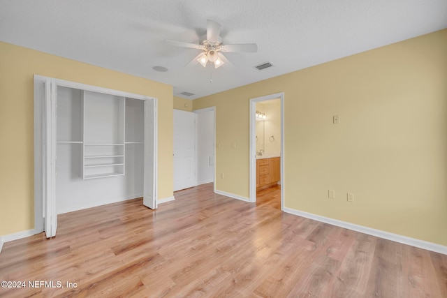 unfurnished bedroom with a textured ceiling, light wood-type flooring, ceiling fan, and a closet