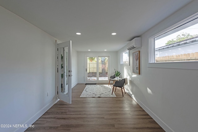 hall with dark hardwood / wood-style flooring, a wall unit AC, and french doors