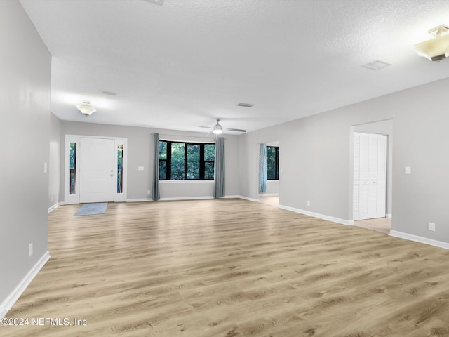 unfurnished living room featuring light wood-type flooring, a textured ceiling, and ceiling fan