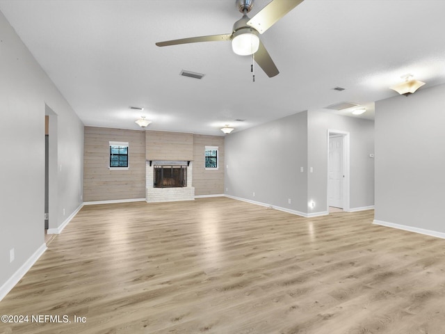 unfurnished living room featuring a brick fireplace, wood-type flooring, and ceiling fan