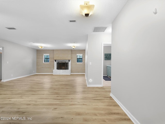 unfurnished living room with a fireplace, light hardwood / wood-style floors, and a textured ceiling