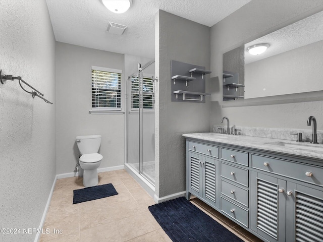 bathroom with toilet, a shower with door, tile patterned flooring, a textured ceiling, and vanity