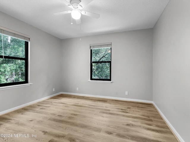 spare room featuring a wealth of natural light, ceiling fan, and light hardwood / wood-style flooring