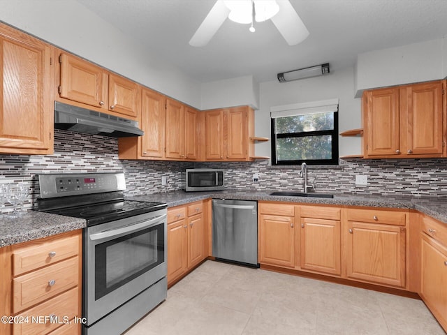 kitchen with appliances with stainless steel finishes, light tile patterned floors, decorative backsplash, sink, and ceiling fan