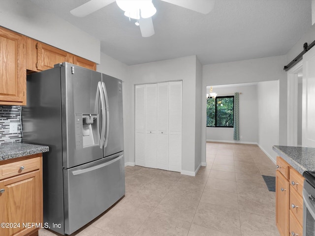 kitchen featuring backsplash, appliances with stainless steel finishes, a barn door, a textured ceiling, and ceiling fan