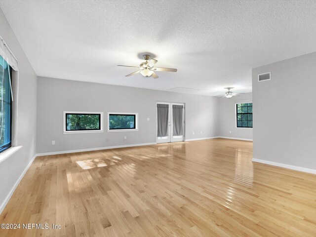 unfurnished living room featuring light hardwood / wood-style floors, ceiling fan, and a textured ceiling