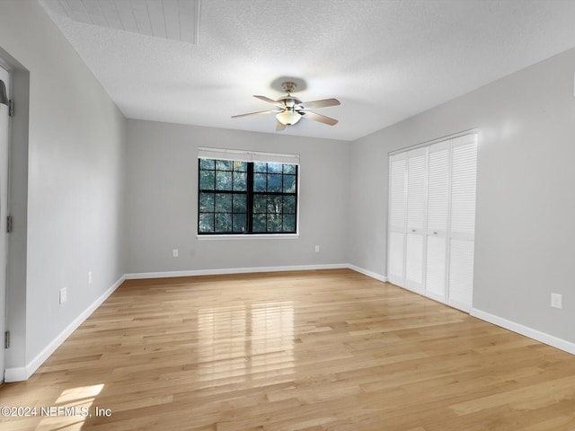 unfurnished bedroom with a closet, a textured ceiling, ceiling fan, and light hardwood / wood-style flooring