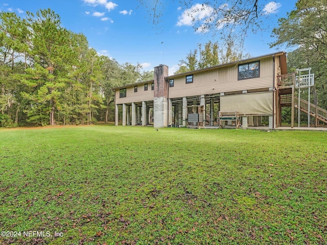 rear view of property with a yard and a wooden deck