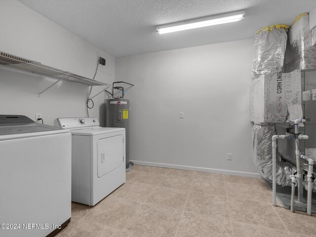 washroom featuring a textured ceiling, water heater, washing machine and dryer, and light tile patterned flooring