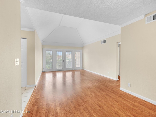 unfurnished living room with vaulted ceiling, ornamental molding, a textured ceiling, and light hardwood / wood-style floors