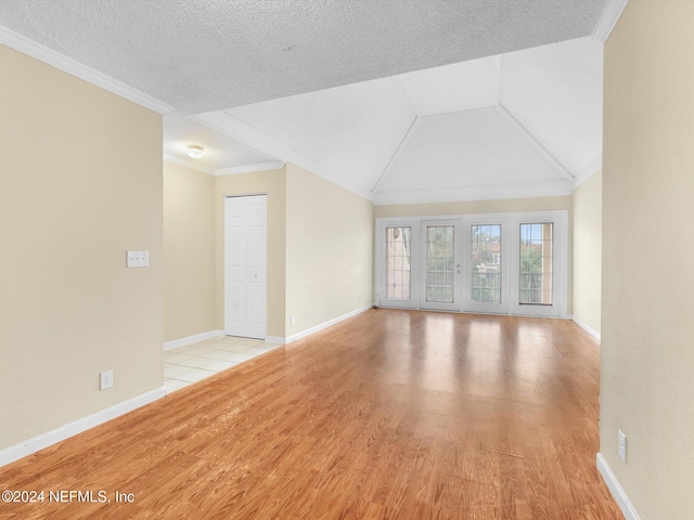 unfurnished living room with vaulted ceiling, ornamental molding, a textured ceiling, and light wood-type flooring