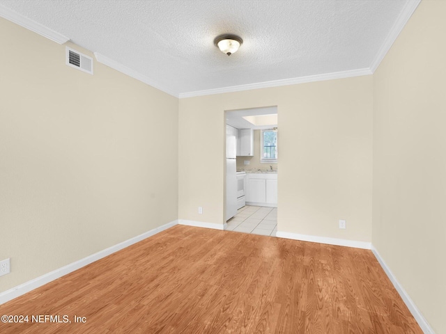 empty room with ornamental molding, a textured ceiling, and light hardwood / wood-style floors