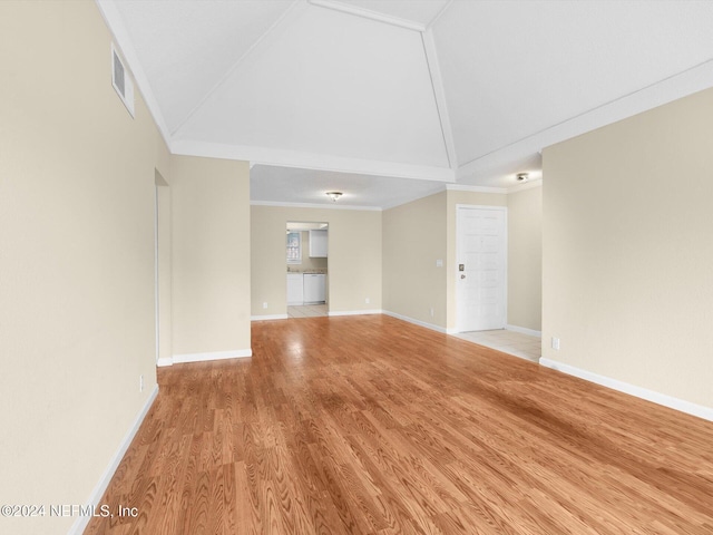 empty room featuring crown molding, high vaulted ceiling, and light wood-type flooring