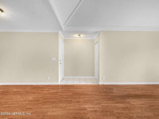 spare room with ornamental molding, a textured ceiling, and light hardwood / wood-style floors