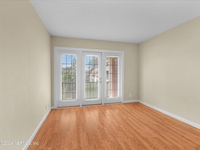 spare room featuring light hardwood / wood-style floors and a textured ceiling