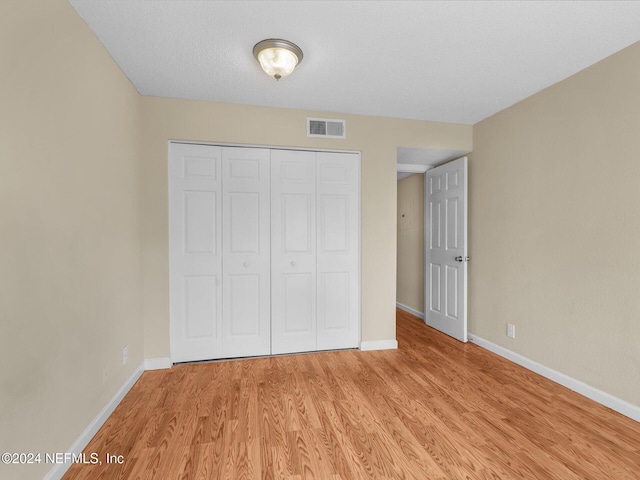 unfurnished bedroom featuring light hardwood / wood-style floors and a closet