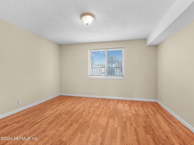 unfurnished room with a textured ceiling and light wood-type flooring