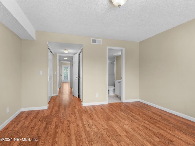 empty room with light hardwood / wood-style floors and a textured ceiling