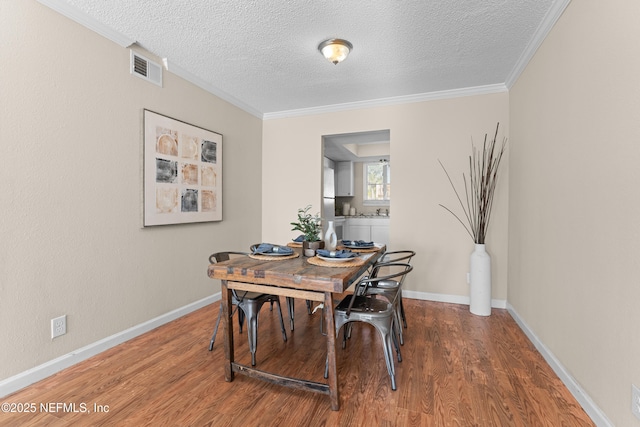 dining room with hardwood / wood-style flooring, ornamental molding, and a textured ceiling