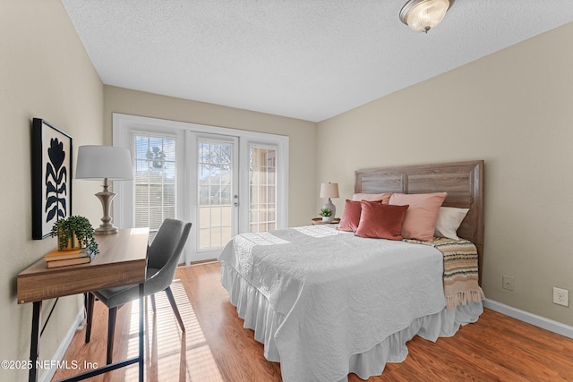 bedroom with access to exterior, a textured ceiling, and light wood-type flooring