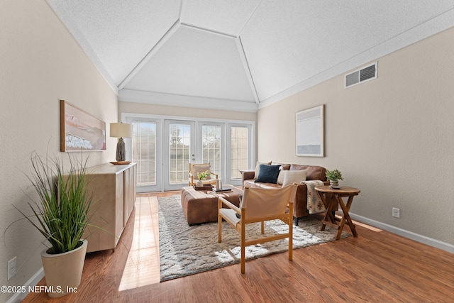 living room featuring french doors, lofted ceiling, a textured ceiling, and hardwood / wood-style flooring