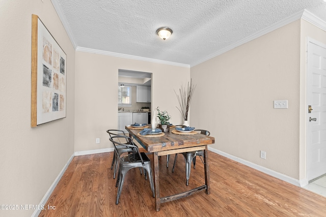 dining area featuring light hardwood / wood-style flooring, ornamental molding, and a textured ceiling