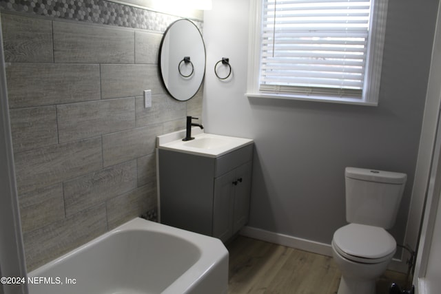 bathroom featuring hardwood / wood-style floors, toilet, a bathtub, vanity, and tile walls