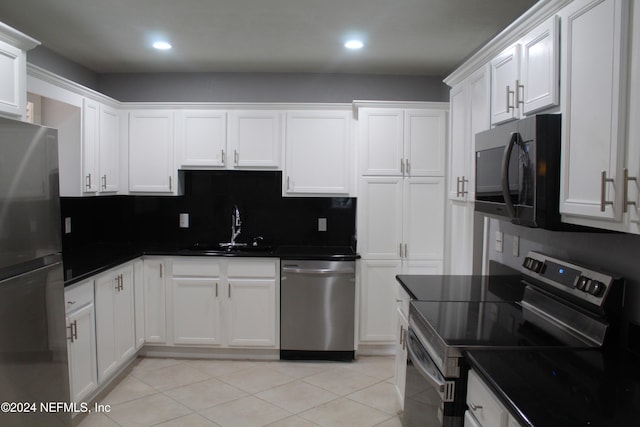 kitchen with decorative backsplash, stainless steel appliances, sink, light tile patterned floors, and white cabinets