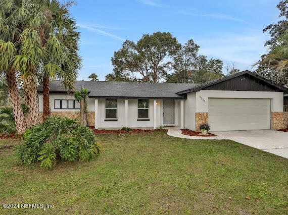 single story home with a garage and a front lawn