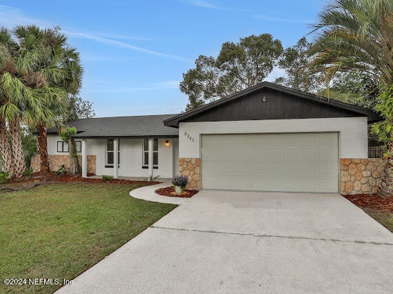 single story home with a garage and a front lawn