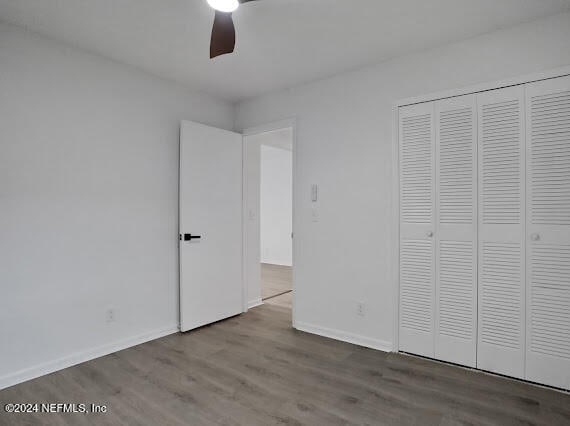 unfurnished bedroom featuring ceiling fan, wood-type flooring, and a closet