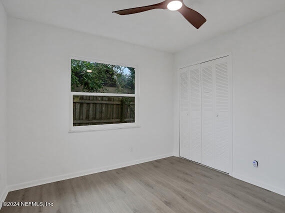 unfurnished bedroom featuring hardwood / wood-style floors, ceiling fan, and a closet