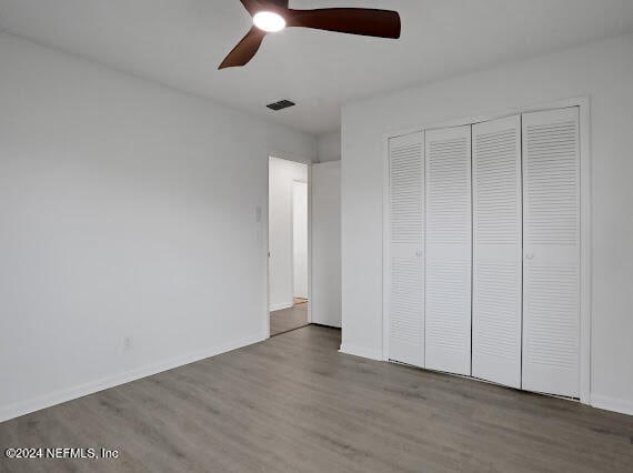 unfurnished bedroom featuring a closet, wood-type flooring, and ceiling fan