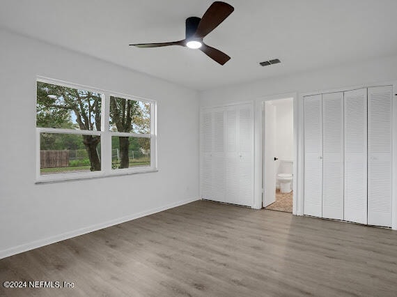 unfurnished bedroom with connected bathroom, hardwood / wood-style flooring, and ceiling fan